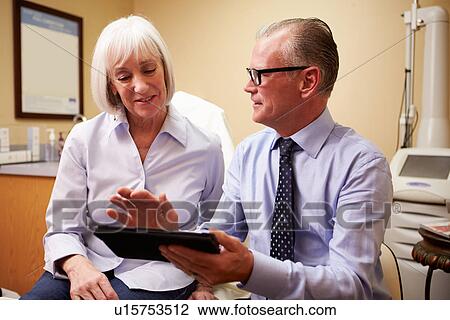 Stock Image - Cosmetic Surgeon Discussing Proceedure With Client In Office. Fotosearch