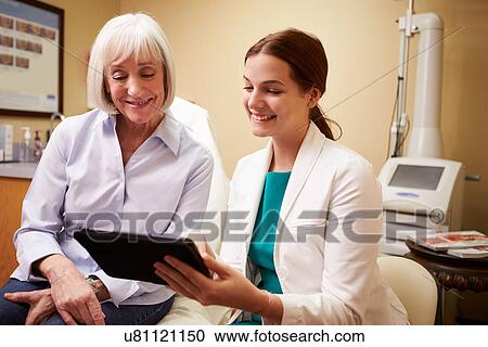 Stock Image - Cosmetic Surgeon Discussing Proceedure With Client In Office. Fotosearch