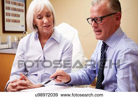 Stock Photo - Cosmetic Surgeon Discussing Proceedure With Client In Office. Fotosearch
