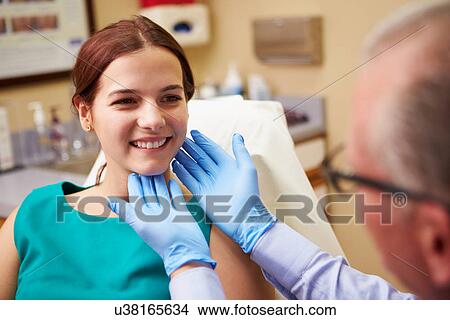 Picture - Cosmetic Surgeon Examining Female Client In Office. Fotosearch