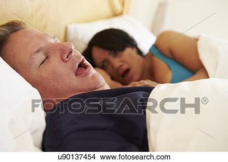 Picture - Couple Asleep In Bed With Man Snoring. Fotosearch