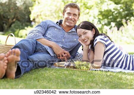 Stock Image - Couple in park with picnic. Fotosearch