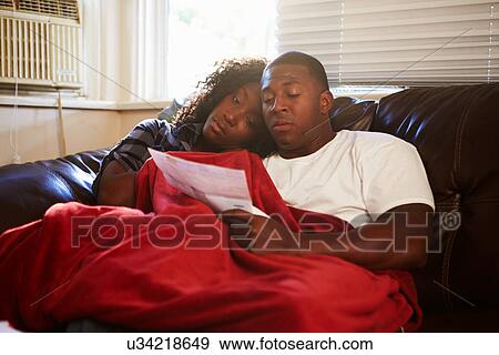 Couple Looking At Bills Keeping Warm Under Blanket At Home View Large Photo Image Stock Photo - Couple Looking At Bills Keeping Warm Under Blanket At Home. Fotosearch