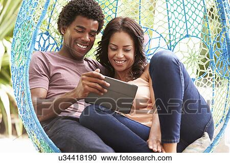Couple On Outdoor Garden Swing Seat Using Digital Tablet View Large Photo Image Stock Image - Couple On Outdoor Garden Swing Seat Using Digital Tablet. Fotosearch