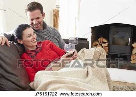 Stock Image - Couple Relaxing At Home Drinking Wine. Fotosearch