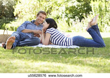 Couple relaxing in park View Large Photo Image Stock Photograph - Couple relaxing in park. Fotosearch