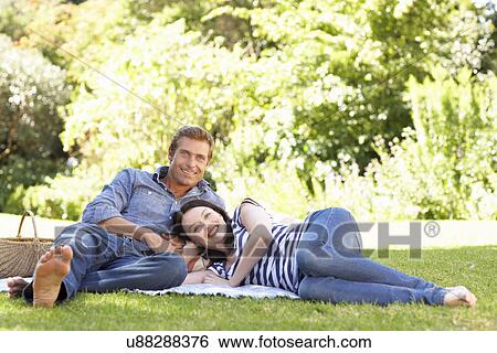 Couple relaxing in park View Large Photo Image Stock Photograph - Couple relaxing in park. Fotosearch