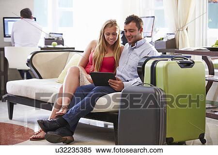 Couple Sitting In Hotel Lobby Looking At Digital Tablet View Large Photo Image Stock Photography - Couple Sitting In Hotel Lobby Looking At Digital Tablet. Fotosearch