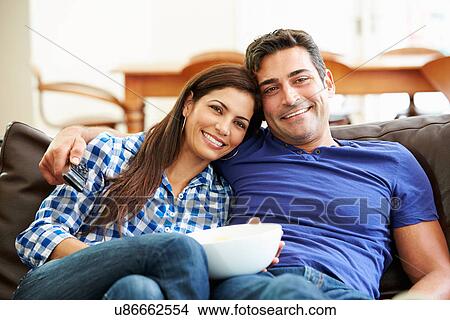Couple Sitting On Sofa Watching TV Together View Large Photo Image Picture - Couple Sitting On Sofa Watching TV Together. Fotosearch