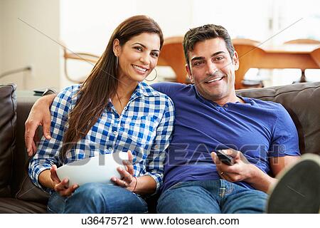 Couple Sitting On Sofa Watching TV Together View Large Photo Image Stock Image - Couple Sitting On Sofa Watching TV Together. Fotosearch