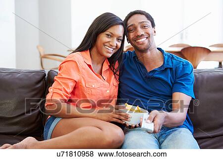 Couple Sitting On Sofa Watching TV Together View Large Photo Image Stock Photo - Couple Sitting On Sofa Watching TV Together. Fotosearch