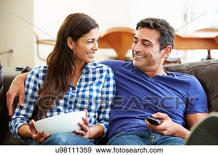 Couple Sitting On Sofa Watching TV Together View Large Photo Image Stock Photo - Couple Sitting On Sofa Watching TV Together. Fotosearch