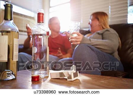 Couple Sitting On Sofa With Bottle Of Vodka And Cigarettes View Large Photo Image Stock Image - Couple Sitting On Sofa With Bottle Of Vodka And Cigarettes. Fotosearch