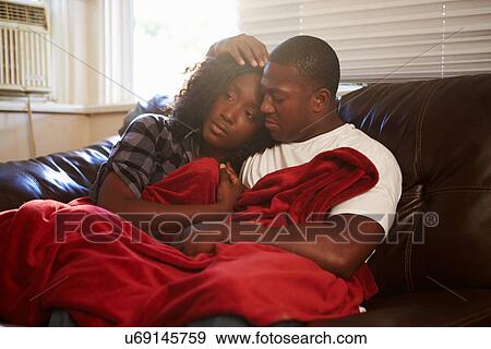 Stock Photo - Couple Trying To Keep Warm Under Blanket At Home. Fotosearch
