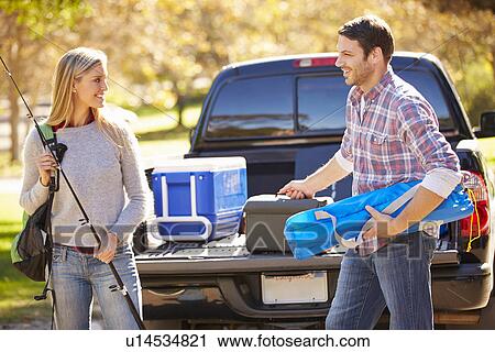 Stock Image - Couple Unpacking Pick Up Truck On Camping Holiday. Fotosearch