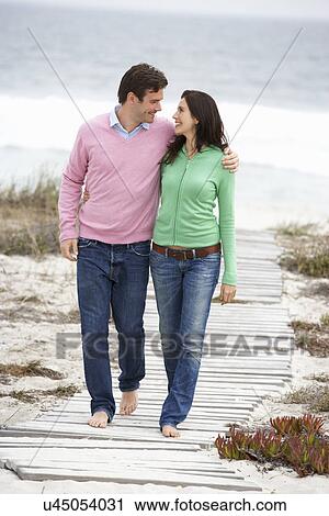 Stock Image - Couple walking by the sea. Fotosearch