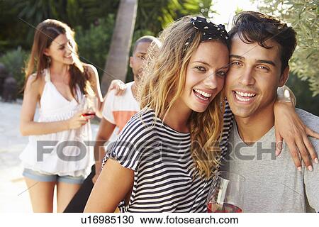 Stock Image - Couple With Friends Drinking Wine And Relaxing Outdoors. Fotosearch