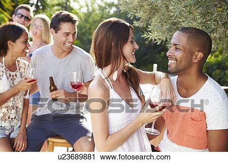 Stock Image - Couple With Friends Drinking Wine And Relaxing Outdoors. Fotosearch