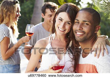 Stock Image - Couple With Friends Drinking Wine And Relaxing Outdoors. Fotosearch
