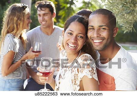 Stock Image - Couple With Friends Drinking Wine And Relaxing Outdoors. Fotosearch