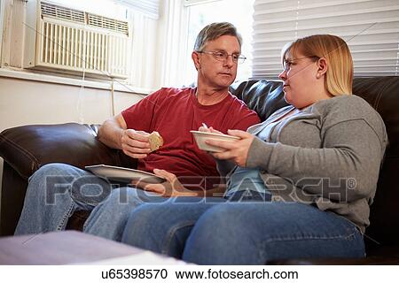 Couple With Poor Diet Sitting On Sofa Eating Meal View Large Photo Image Stock Image - Couple With Poor Diet Sitting On Sofa Eating Meal. Fotosearch