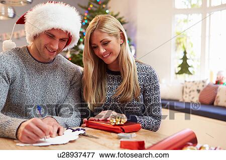 Stock Photo - Couple Wrapping Christmas Gifts At Home. Fotosearch