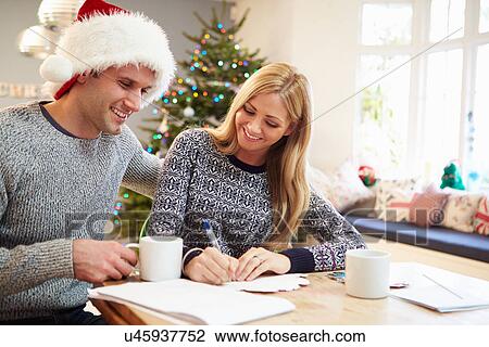 Stock Image - Couple Writing Christmas Cards Together. Fotosearch