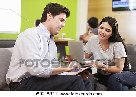 Stock Image - Creatives Having Informal Meeting On Sofas In Design Studio. Fotosearch