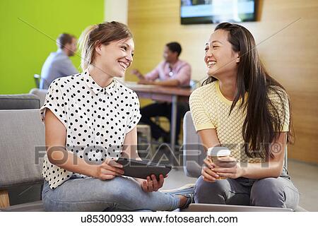 Stock Image - Creatives Having Informal Meeting On Sofas In Design Studio. Fotosearch