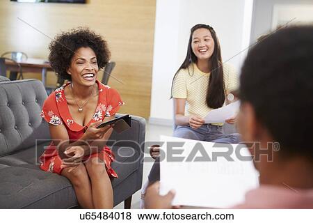 Stock Photo - Creatives Having Informal Meeting On Sofas In Design Studio. Fotosearch