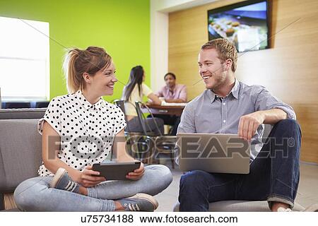 Stock Photo - Creatives Having Informal Meeting On Sofas In Design Studio. Fotosearch