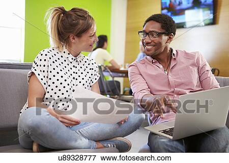 Stock Photo - Creatives Having Informal Meeting On Sofas In Design Studio. Fotosearch