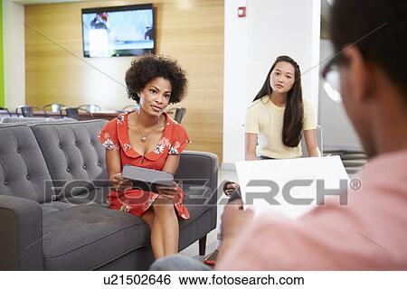 Stock Photograph - Creatives Having Informal Meeting On Sofas In Design Studio. Fotosearch