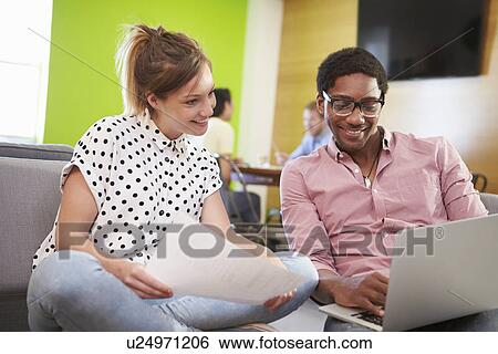 Stock Photograph - Creatives Having Informal Meeting On Sofas In Design Studio. Fotosearch