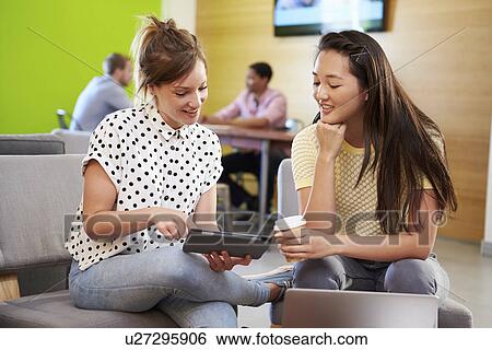 Stock Photograph - Creatives Having Informal Meeting On Sofas In Design Studio. Fotosearch