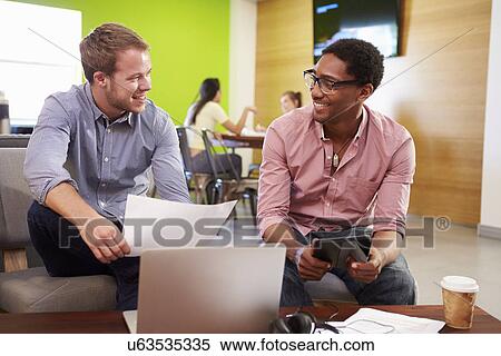 Stock Photography - Creatives Having Informal Meeting On Sofas In Design Studio. Fotosearch