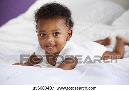 Stock Photo - Cute Baby Lying On Tummy In Parent's Bed. Fotosearch