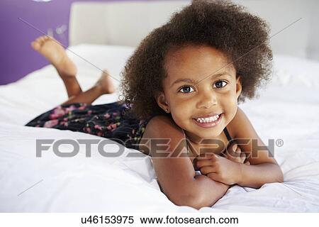 Stock Photography - Cute Little Girl Lying On Tummy In Parent's Bed. Fotosearch