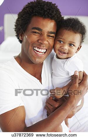 Stock Photo - Dad Cuddling Baby Son At Home. Fotosearch