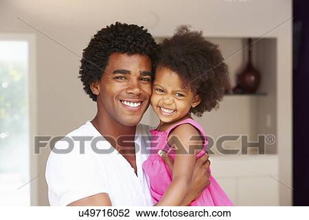 Stock Image - Dad Cuddling Daughter At Home. Fotosearch