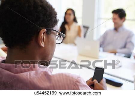Designer Using Mobile Phone During Meeting View Large Photo Image Stock Photo - Designer Using Mobile Phone During Meeting. Fotosearch