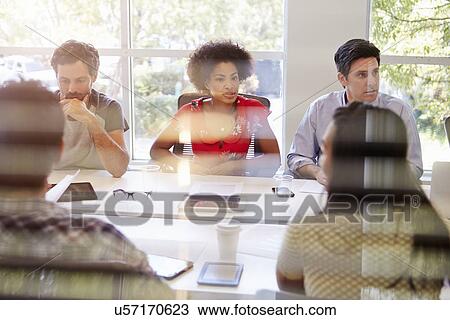 Stock Image - Designers Having Meeting Viewed Through Window. Fotosearch