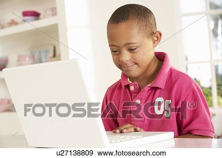 Stock Photo - Downs Syndrome boy with laptop. Fotosearch