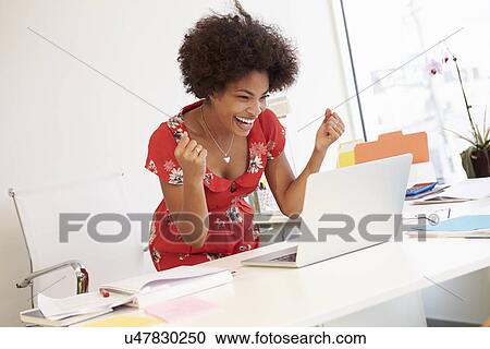 Stock Image - Excited Woman Working At Desk In Design Studio . Fotosearch