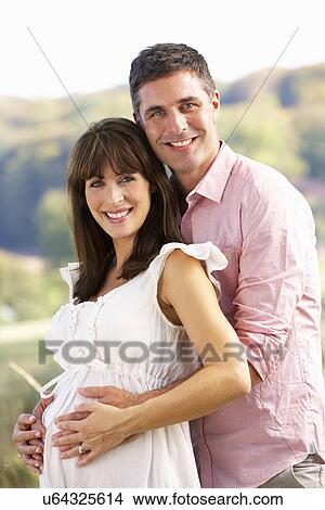 Picture - Expectant couple outdoors in countryside. Fotosearch