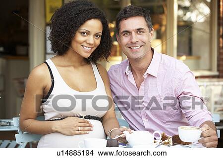 Expectant couple sitting outside café View Large Photo Image Picture - Expectant couple sitting outside café. Fotosearch