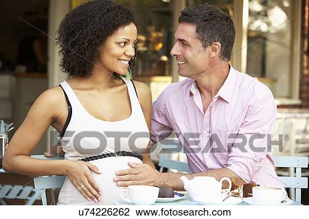 Expectant couple sitting outside café View Large Photo Image Stock Image - Expectant couple sitting outside café. Fotosearch