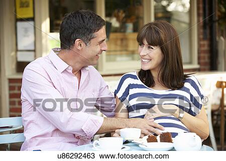 Stock Image - Expectant couple sitting outside café. Fotosearch