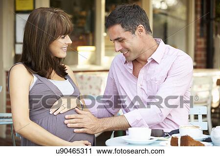 Stock Image - Expectant couple sitting outside café. Fotosearch