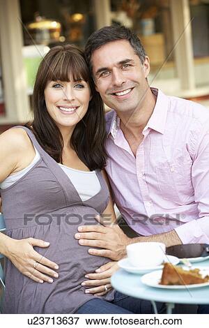 Expectant couple sitting outside café View Large Photo Image Stock Photo - Expectant couple sitting outside café. Fotosearch